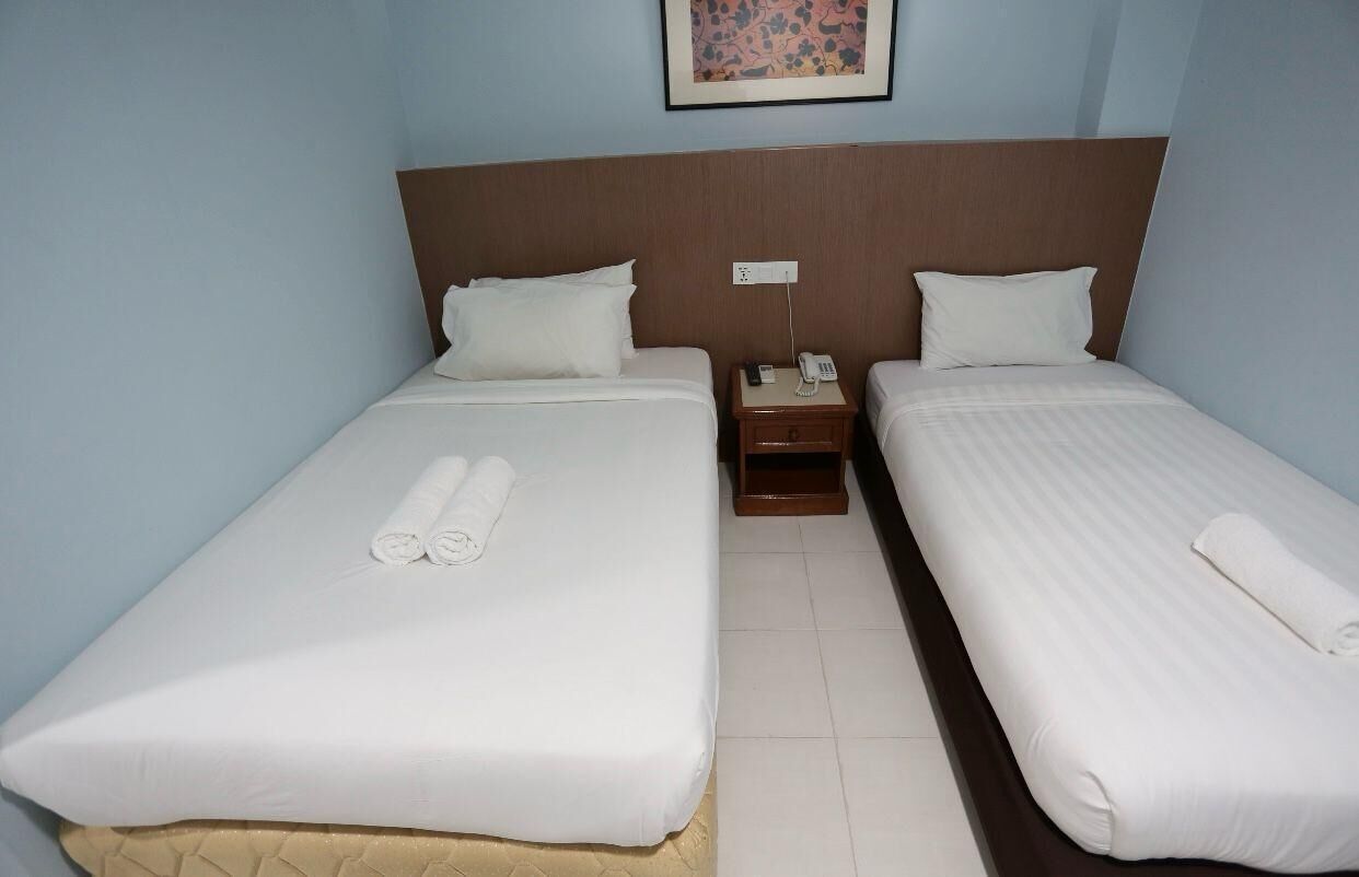 A hotel room with two beds, a nightstand with a phone, and a painting on the wall.