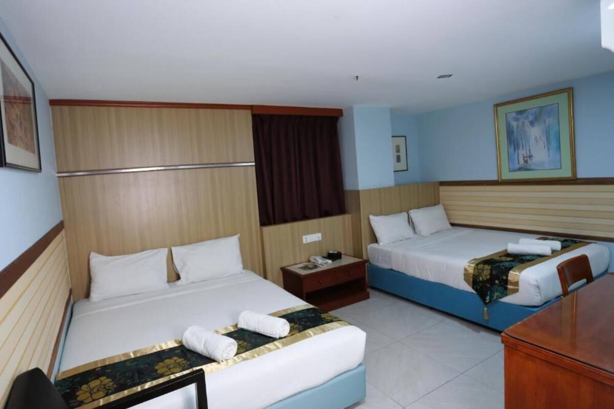 Habitación de hotel con dos camas, cabecero de madera, mesita de noche y un cuadro en la pared.