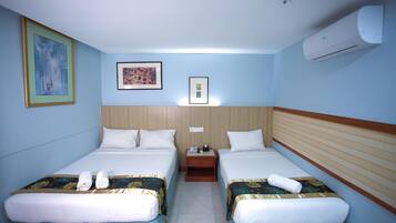 A hotel room with two beds, a nightstand, and an air conditioning unit.