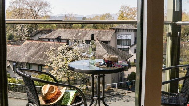 Un balcón con mesa, sillas y vistas a edificios tradicionales y árboles.
