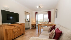 Una sala de estar acogedora con un mueble de televisión de madera, un sofá y un comedor con una mesa y sillas.
