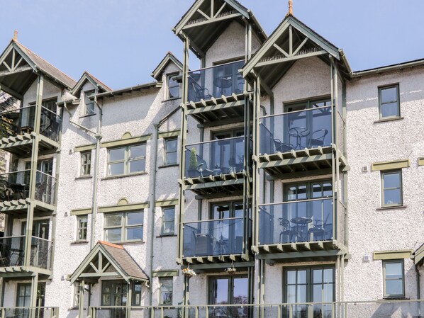 A multi-story building with balconies, large windows, and a textured facade.