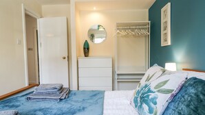 Un dormitorio con cama, cómoda, espejo y armario.