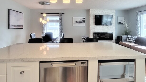 A modern kitchen with a central island, stainless steel appliances, and pendant lighting.