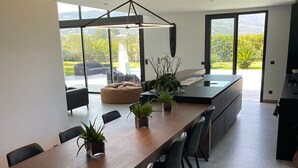 Una cocina moderna con una mesa de madera larga, sillas negras y plantas en macetas.