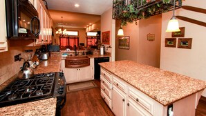 A kitchen with granite countertops, a stove, and white cabinetry. - Boulder Bay Lakefront. Dock, hot tub, BBQ, fire pit, pool table. Large backyard. (Big Bear Lake)