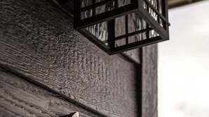 A wooden door with a metal number plate and a black lantern above it.
