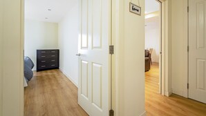 A hallway with a wooden floor, a black dresser, and a white door with a 'home' sign. - Bell Street Apartment (Glasgow)