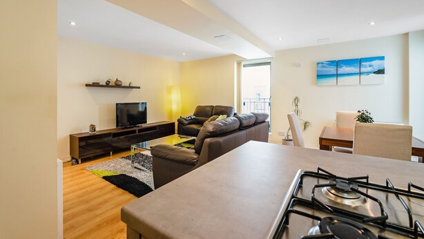 A modern living room with a sofa, TV, and a dining area with a table and chairs. - Bell Street Apartment (Glasgow)