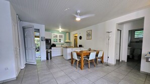 A spacious kitchen with a dining area, white cabinets, a ceiling fan, and a view of the outdoors.