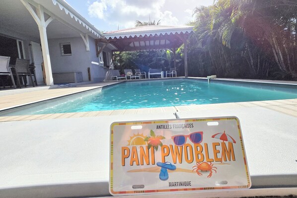 A swimming pool with lounge chairs and a sign reading 'PANT PWBLEM MARTINIQUE'. - Villa Carpe Diem - Swimming Pool - Sleeps 9 - 4 Bedrooms (Les Trois-Îlets)