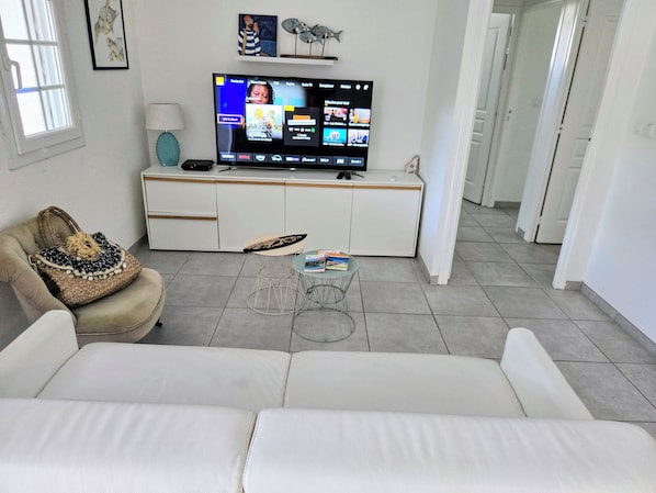 Ein modernes Wohnzimmer mit einer Couch, einem Couchtisch, einem Fernseher auf einem Schrank und einer Wanddekoration.