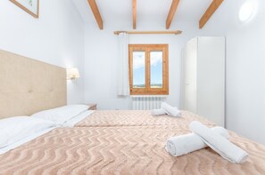 Un dormitorio con cama, ventana con vistas, radiador y armario.