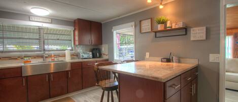 A modern kitchen with a large island, stainless steel appliances, and a view to the outside.