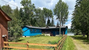 Una casa azul con terraza de madera y patio cercado.