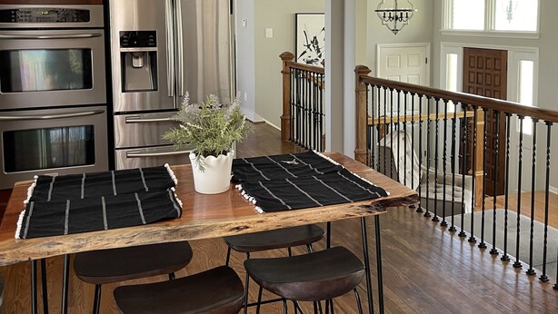 Una cocina con electrodomésticos de acero inoxidable, una isla de madera con taburetes y una escalera que sube a otro nivel.