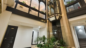 Een ruime atrium met een centrale plantenbak, meerdere balkons met beplanting en een moderne trap.