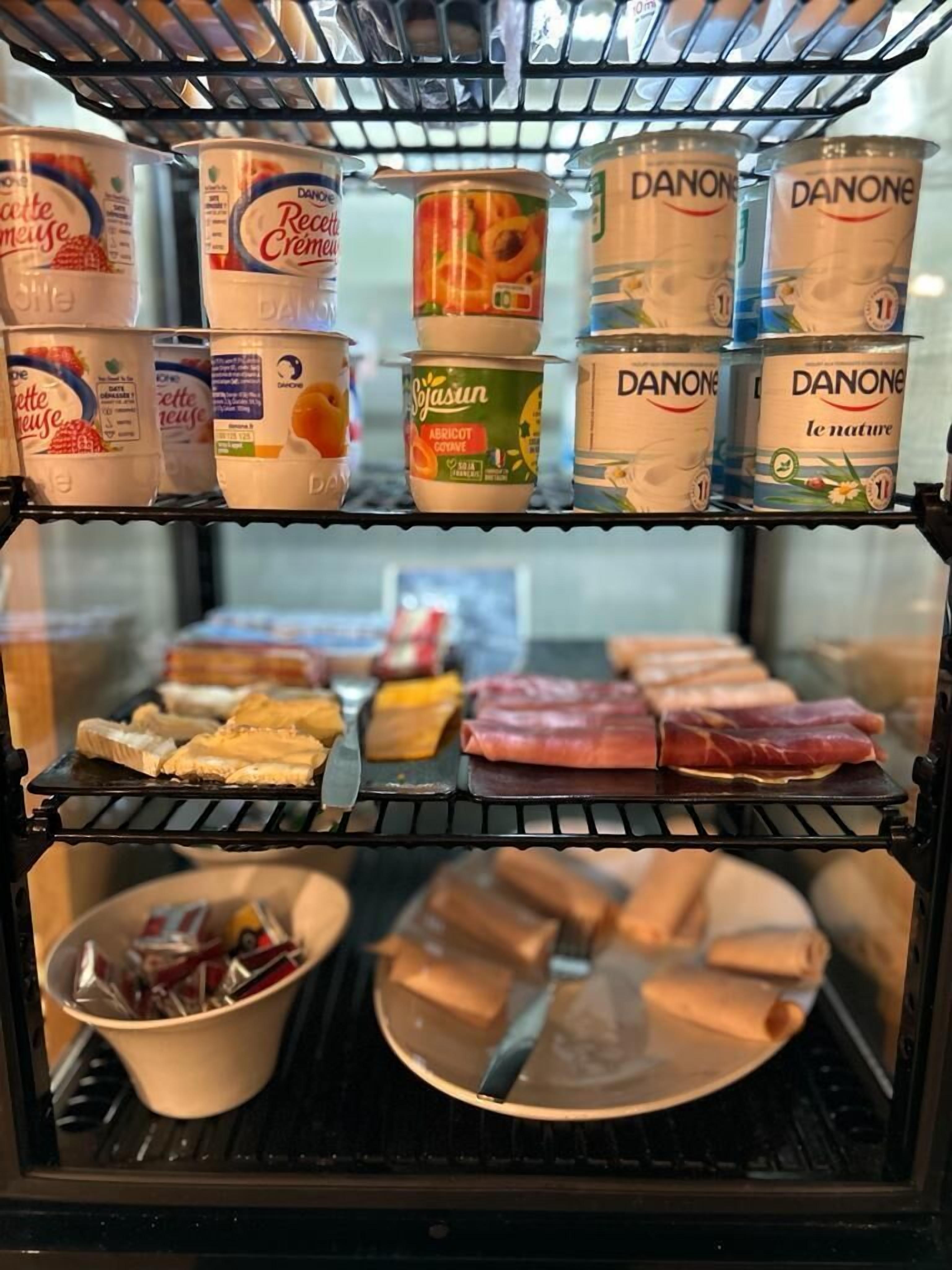 Ett kylskåp med olika livsmedel, inklusive Danones yoghurt och köttprodukter.