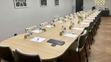 Una sala de conferències amb una taula llarga, cadires, ampolles d'aigua i un teclat.