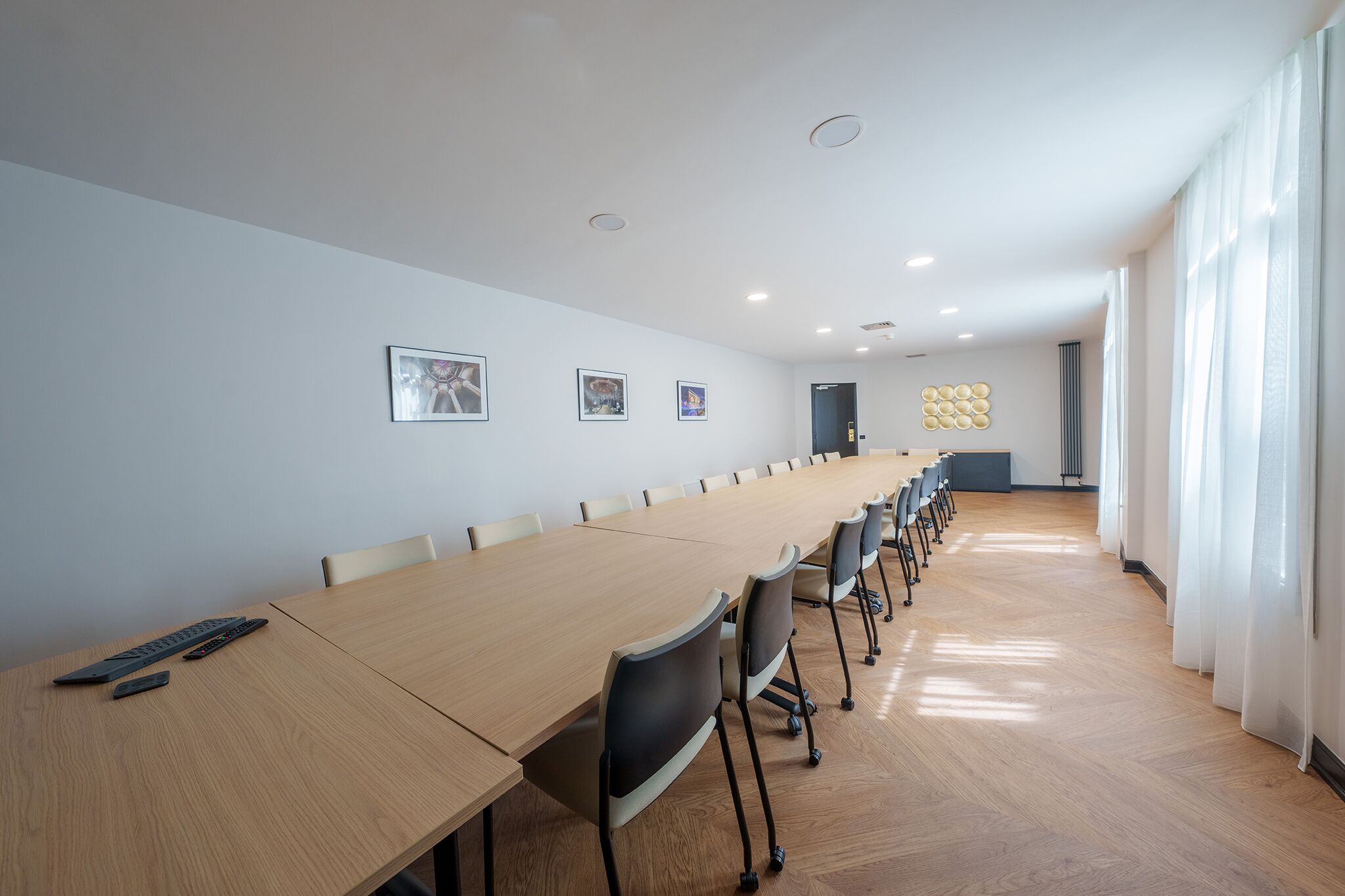 A conference room with a long table, chairs, and ceiling lights.