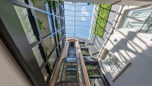 Een modern gebouw met een glazen atrium, meerdere verdiepingen en beplanting.