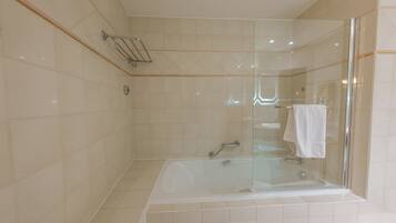 A modern bathroom with a glass-enclosed shower, a standalone bathtub, and a towel rack.