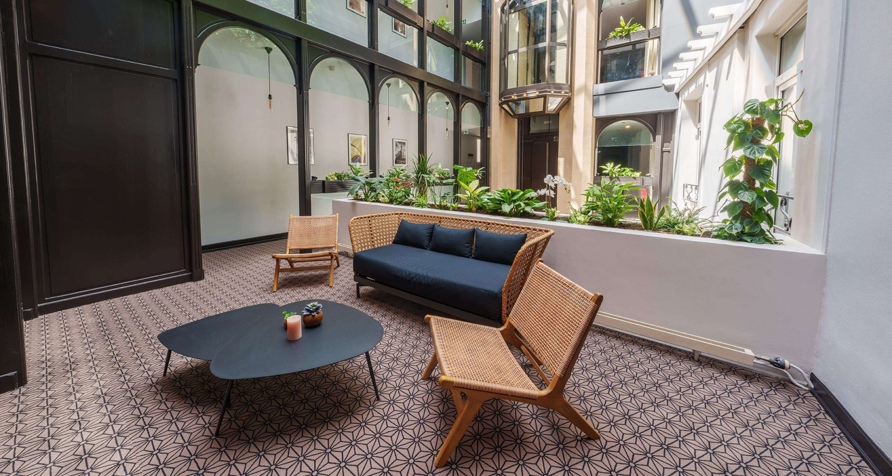 A modern interior with a dark blue sofa, wicker chairs, and a round table.