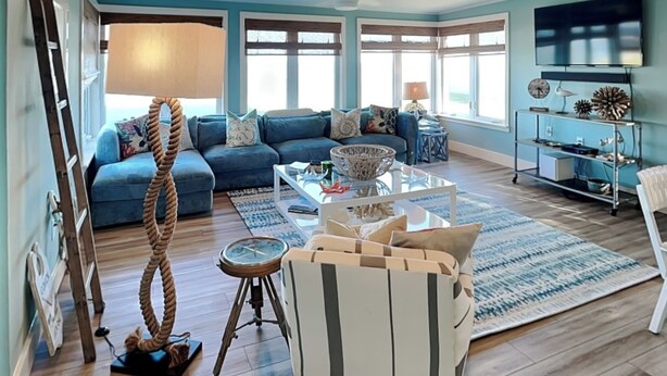 A spacious living room with a blue sofa set, a coffee table, and a TV on a stand. - Ocean Shore by Distinctive Beach Rentals (Flagler Beach)