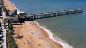 A beach with a pier extending into the water, labeled "FLAGLER BEACH." - Ocean Shore by Distinctive Beach Rentals (Flagler Beach)