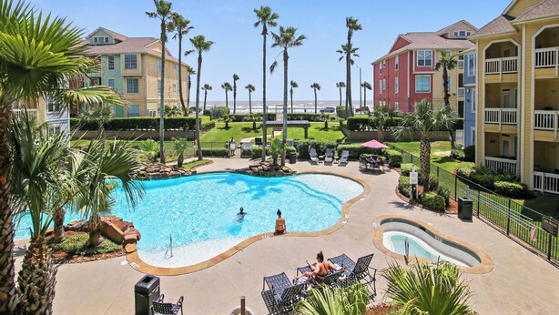 Un resort con piscina, palmeras y vista al océano.