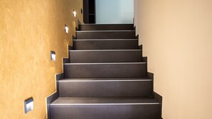 Eine moderne, elegant gestaltete Treppe, die zu einem hellen Gang führt.