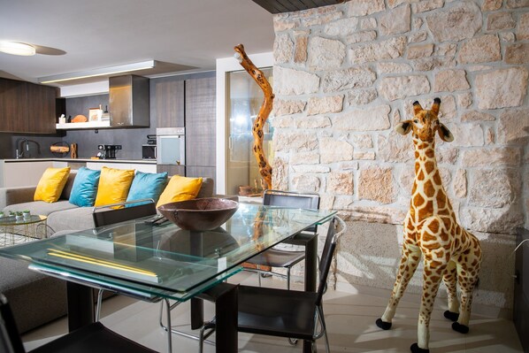 Enjoy a stylish meal for two at this chic dining area, featuring a glass-top table and a unique giraffe sculpture.