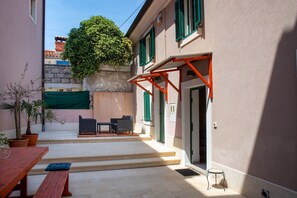 Relax in a charming courtyard with a bench, table, and lush greenery.