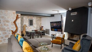 Ein modernes Wohnzimmer mit Steinwand, einer Giraffenskulptur, Kamin und Essbereich.