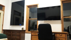 A room with a wooden desk, a black office chair, and a large flat-screen TV mounted on the wall. - Studio in the Heart of East Austin (Austin)