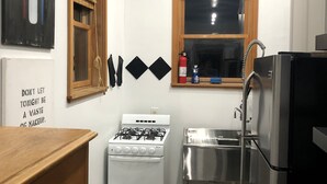 A compact kitchen with a gas stove, stainless steel sink, and a refrigerator. - Studio in the Heart of East Austin (Austin)