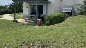 A two-story house with a patio area, a covered seating area, and a small garden.