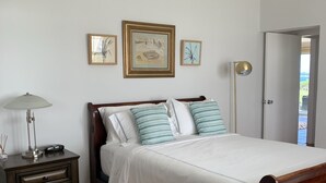 A bedroom with a bed, a nightstand, a lamp, and framed artwork on the wall.