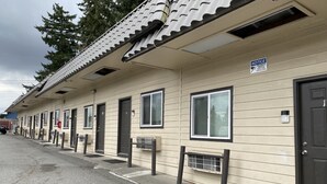 A row of motel rooms with individual doors, windows, and air conditioning units. - Farwest Motel (Everett)