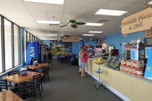 A family-friendly restaurant with a 'Family Fun Zone' sign, a counter with snacks, and a 'Portside Pizza & Deli' sign. - Family-friendly beach condo with balcony, pool, sauna, hot tub, & WiFi (Myrtle Beach)