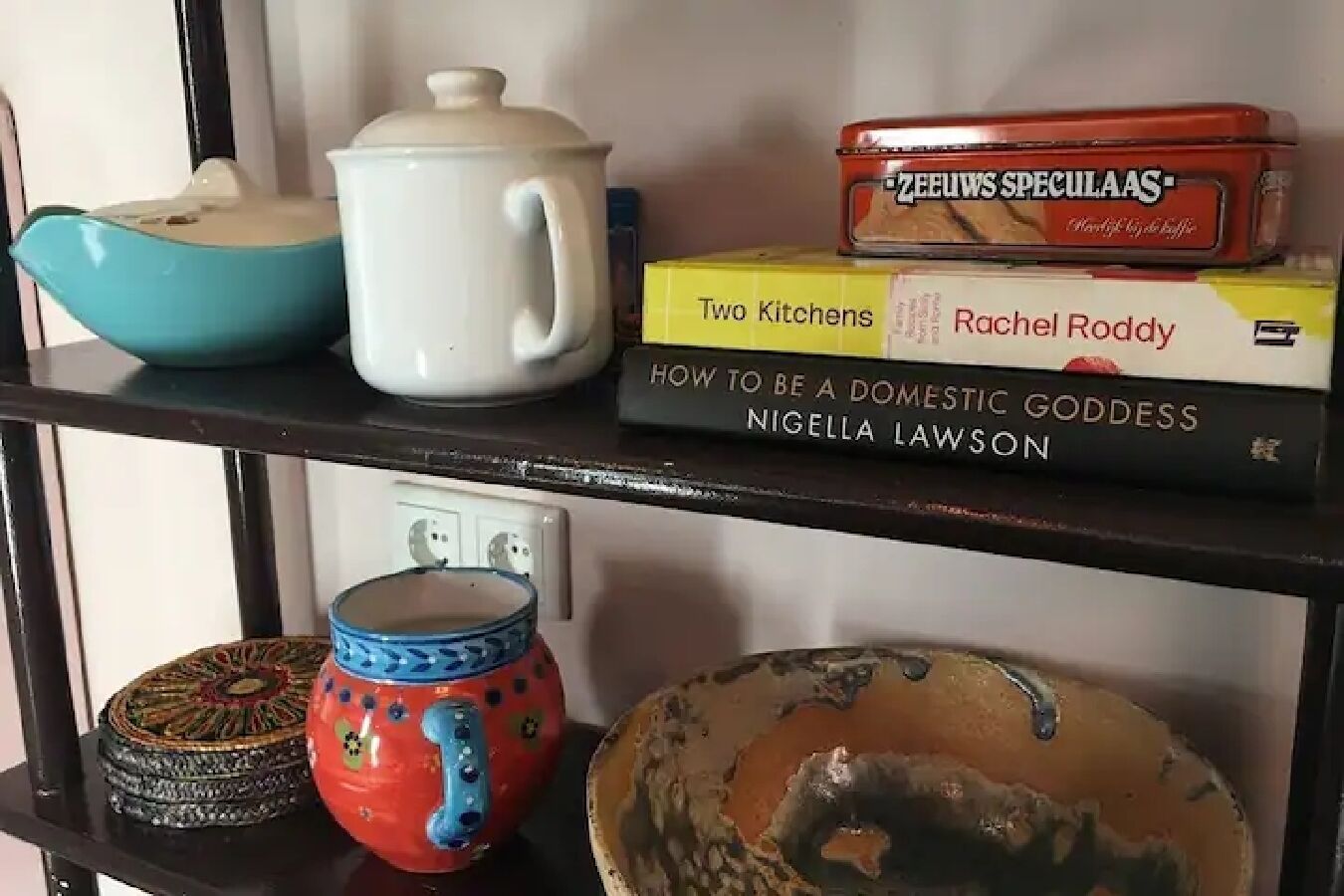 Une étagère avec des ustensiles de cuisine et des livres.