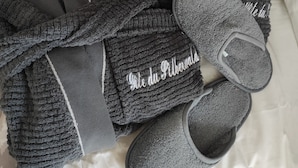 Un par de pantuflas grises y una prenda de punto gris con una etiqueta y texto.