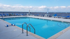 A swimming pool with blue water, surrounded by lounge chairs and a deck.