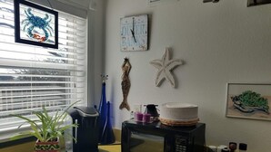 A kitchen with a microwave, a kettle, a potted plant, and a starfish decoration on the wall.