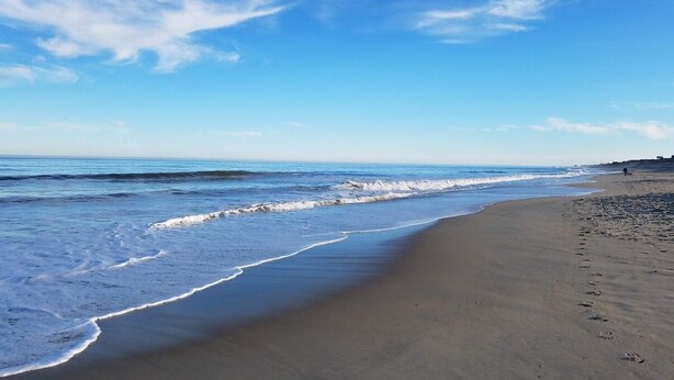 A beach with a wide sandy shore and gentle waves.