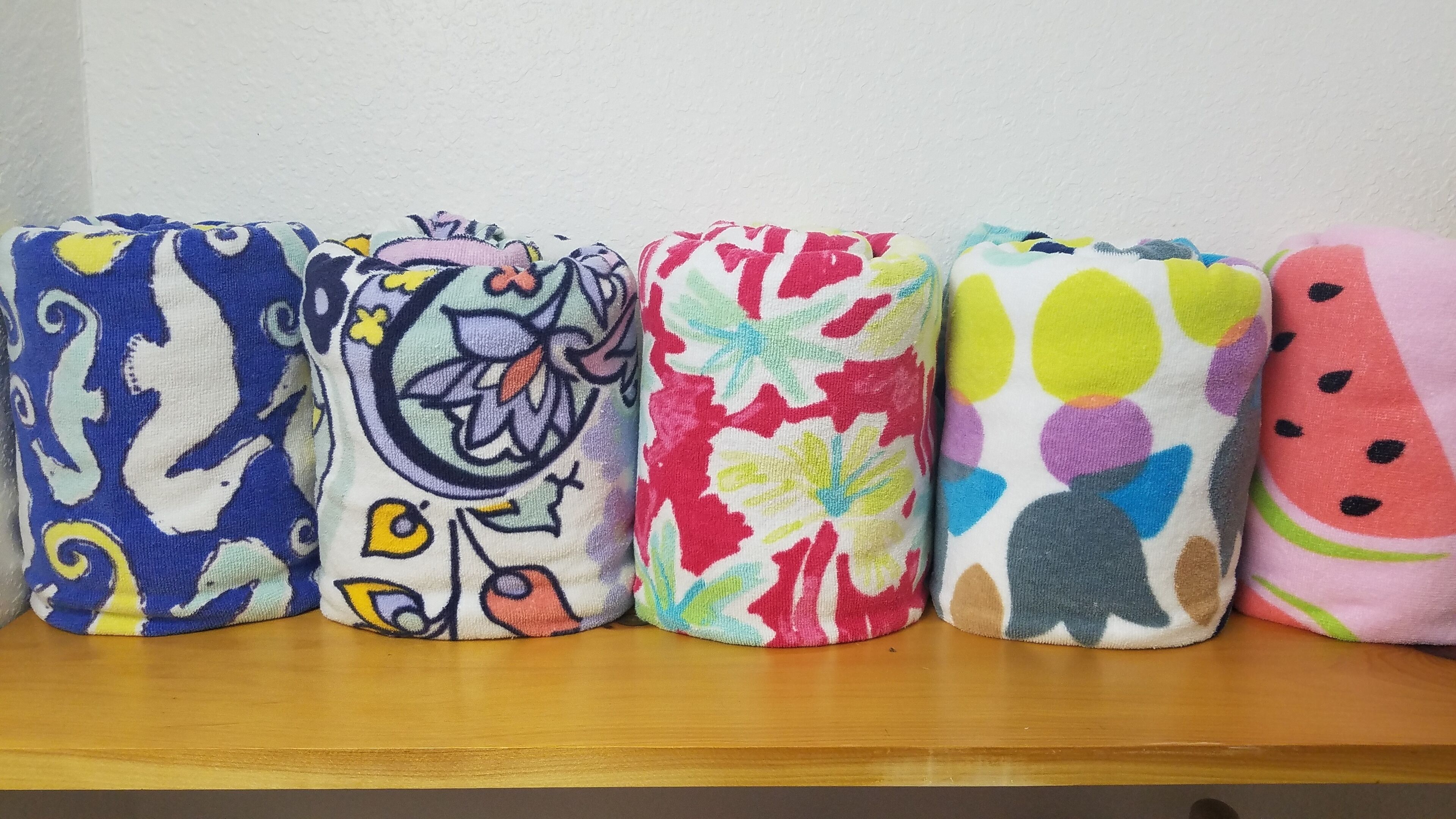 Four rolled-up towels with various colorful patterns.