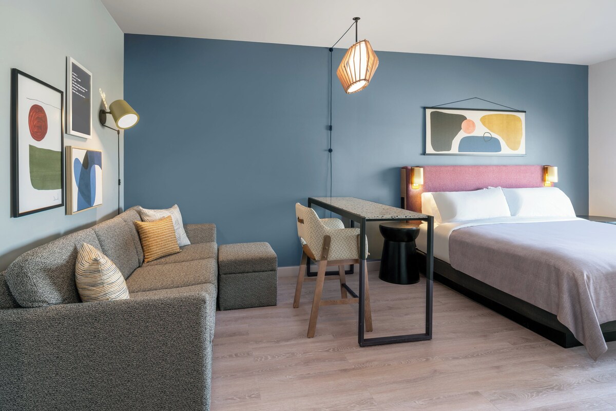 Een moderne slaapkamer met een bed, een bureau, een bank en een stoel.