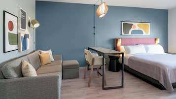 A modern hotel room with a bed, a sofa, a small table, and a chair.