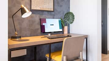 Ein moderner Schreibtisch mit Computer, Lampe und Pflanze.