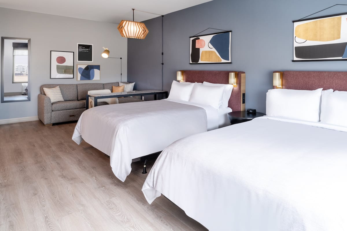 Een moderne hotelkamer met twee bedden, een bank en een eettafel.